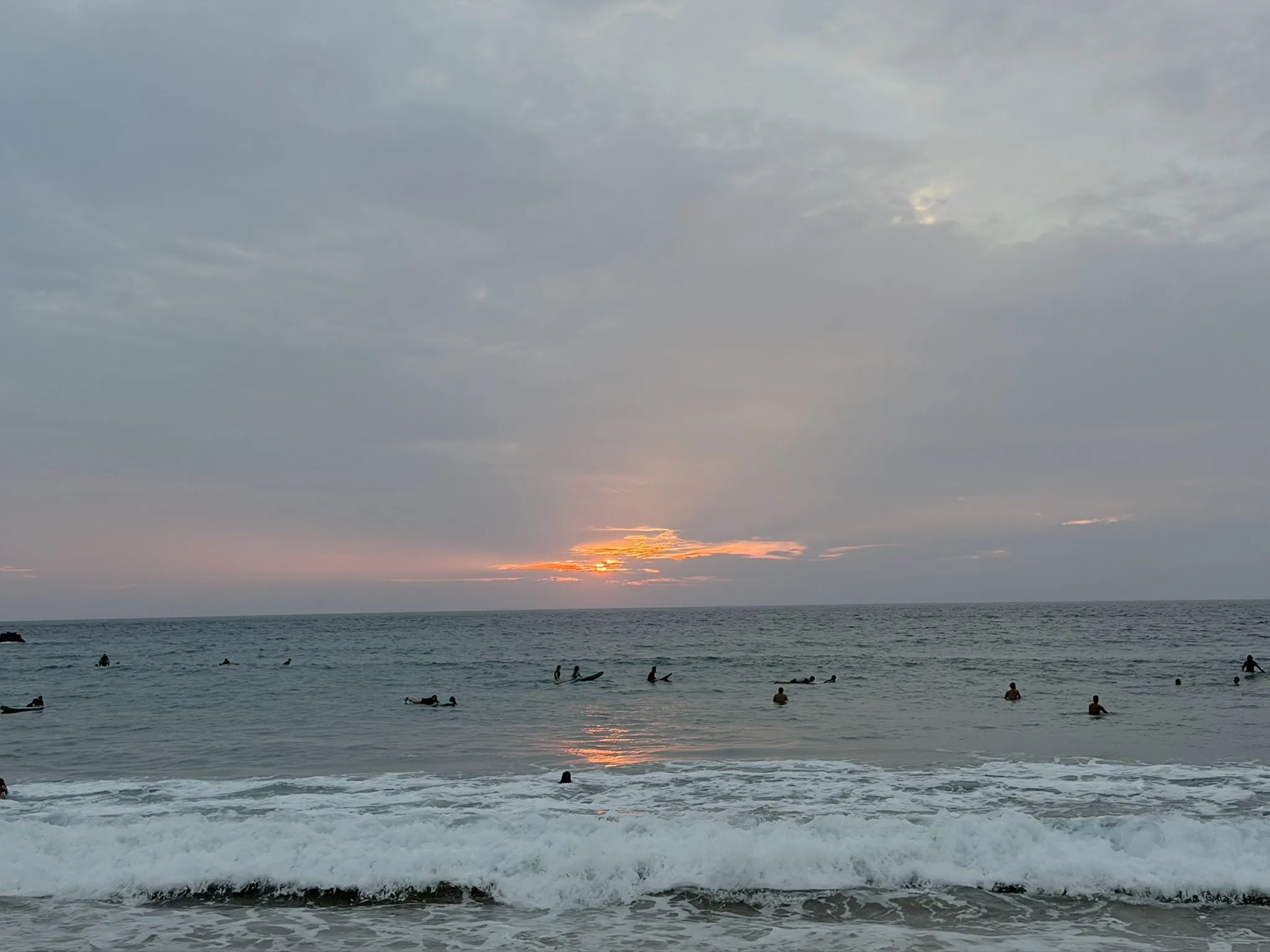 Surfers waiting for waves at sunset on a beach in Puerto Escondido