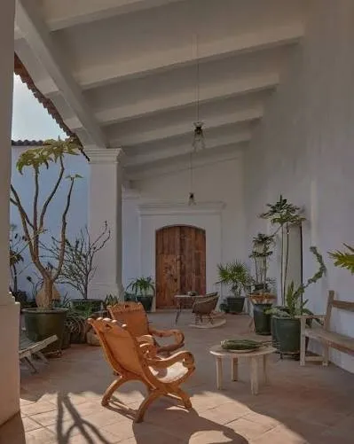Reference image: the restored corridor of an old house, with whitewashed walls, terracotta floors and wooden chairs