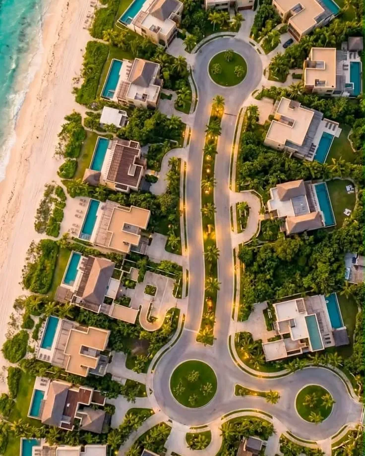 Reference image, not this project: aerial view of a beachfront villa community with pools and palm-lined paths